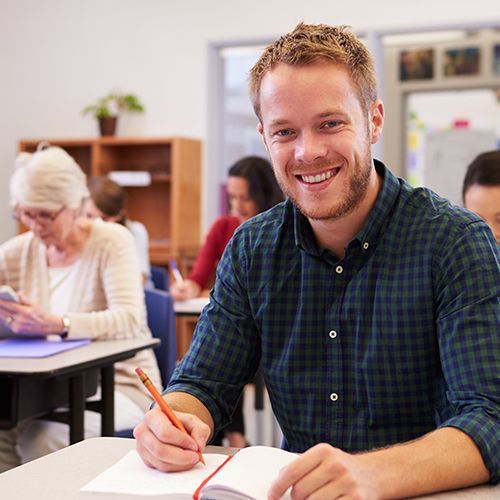 Mann sieht in Kamera und schreibt in Buch