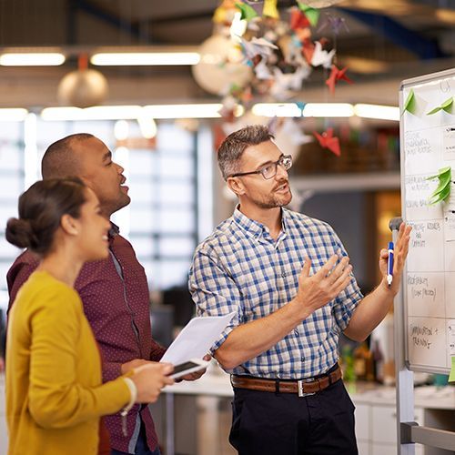 Ein Mann an einer Flipchart erkl&auml;rt zwei anderen Menschen etwas.