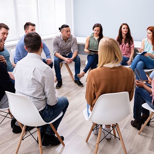 Menschen sitzen in einem Stuhlkreis und unterhalten sich.
