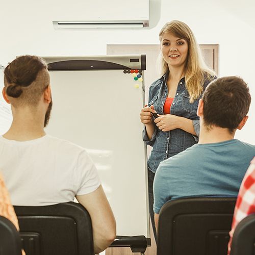 Eine Dozentin steht neben einer Flipchart.