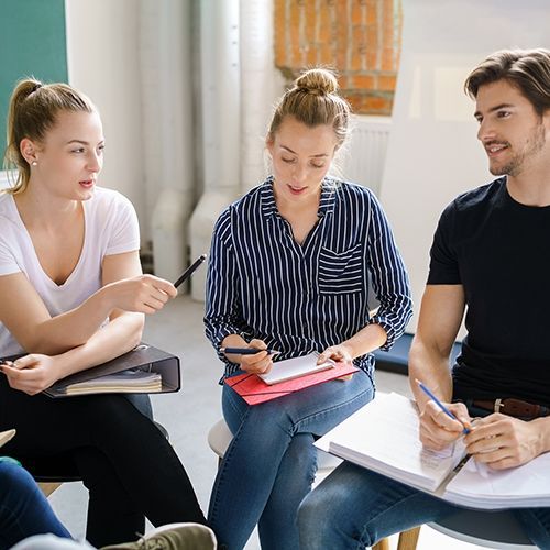 Drei junge Personen sitzen in einem Stuhlkreis und diskutieren.