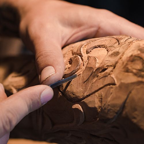 Jemand schnitzt an einem Holz.