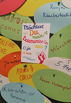 Bunte Karten liegen verteilt übereinander. Auf diesen Karten stehen die Namen verschiedenster Kinderbücher wie "Ronja Räubertochter" oder auch Comics wie "Asterix und Obelix".