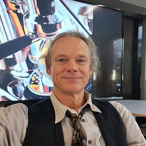 Ein Mann sieht in eine Kamera.