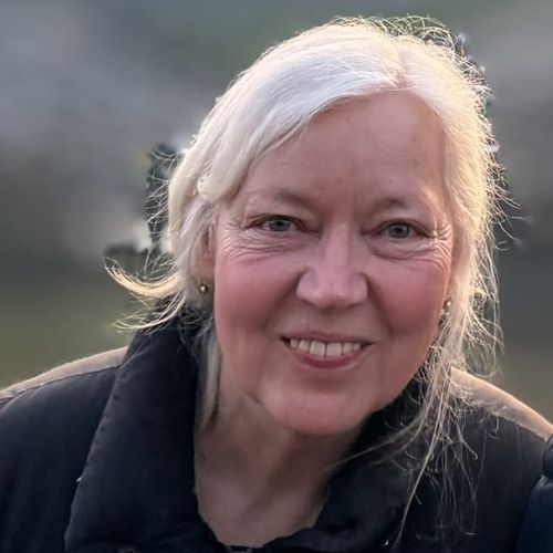 Frau sieht in eine Kamera - im Hintergrund Natur.