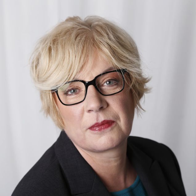 Eine Businessfrau sieht in eine Kamera.